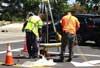 A construction crew work near a manhole to perform cured-in-place point repairs on a sewer pipe.