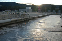 Water in an aeration basin with sun behind hills in background.