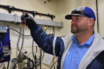 Water/Wastewater Systems Operator III Matt McGrath holds up a glass vial of water turned pink from a chlorine test.