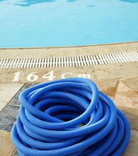 A coiled pool hose next to a swimming pool