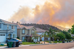 Homes with orange and gray smoke in the background.