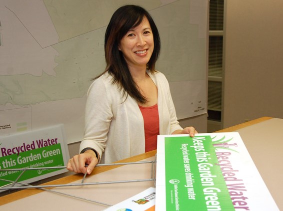 Administrative Assistant II Sara Tom at the Permit Counter with recycled water signs.