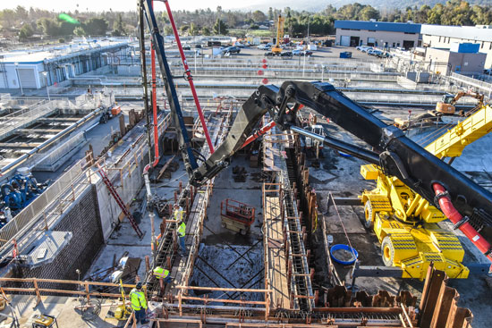 Aerial view of primary treatment tank construction with crane and cement pouring.