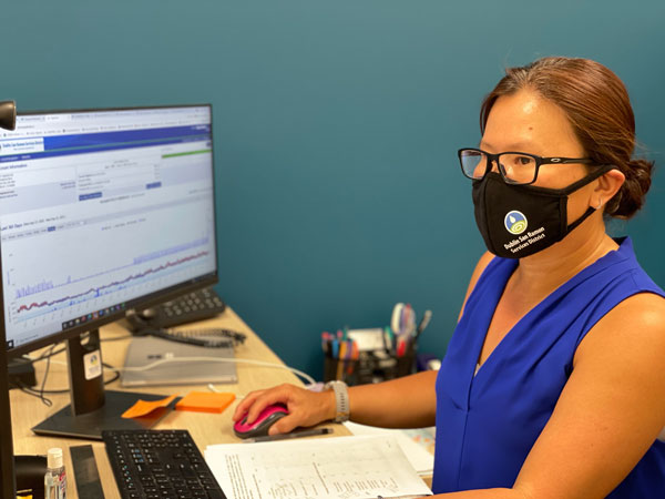 Irene Suroso wears a mask while looking at AquaHawk on her computer