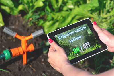 Hands holding a touch-screen tablet for an irrigation system