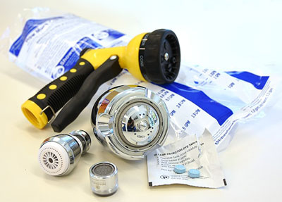 Water conservation giveaways in a pile: yellow and black hose nozzle, sink aerators, showerhead, flow meter bag, toilet dye tab pack