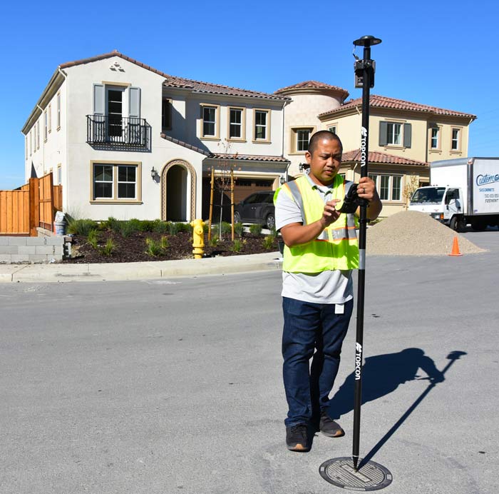 Roper Macaraeg uses a receiver to take exact coordinates of a valve with a home in back.