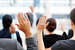 People attending a meeting, raising their hands